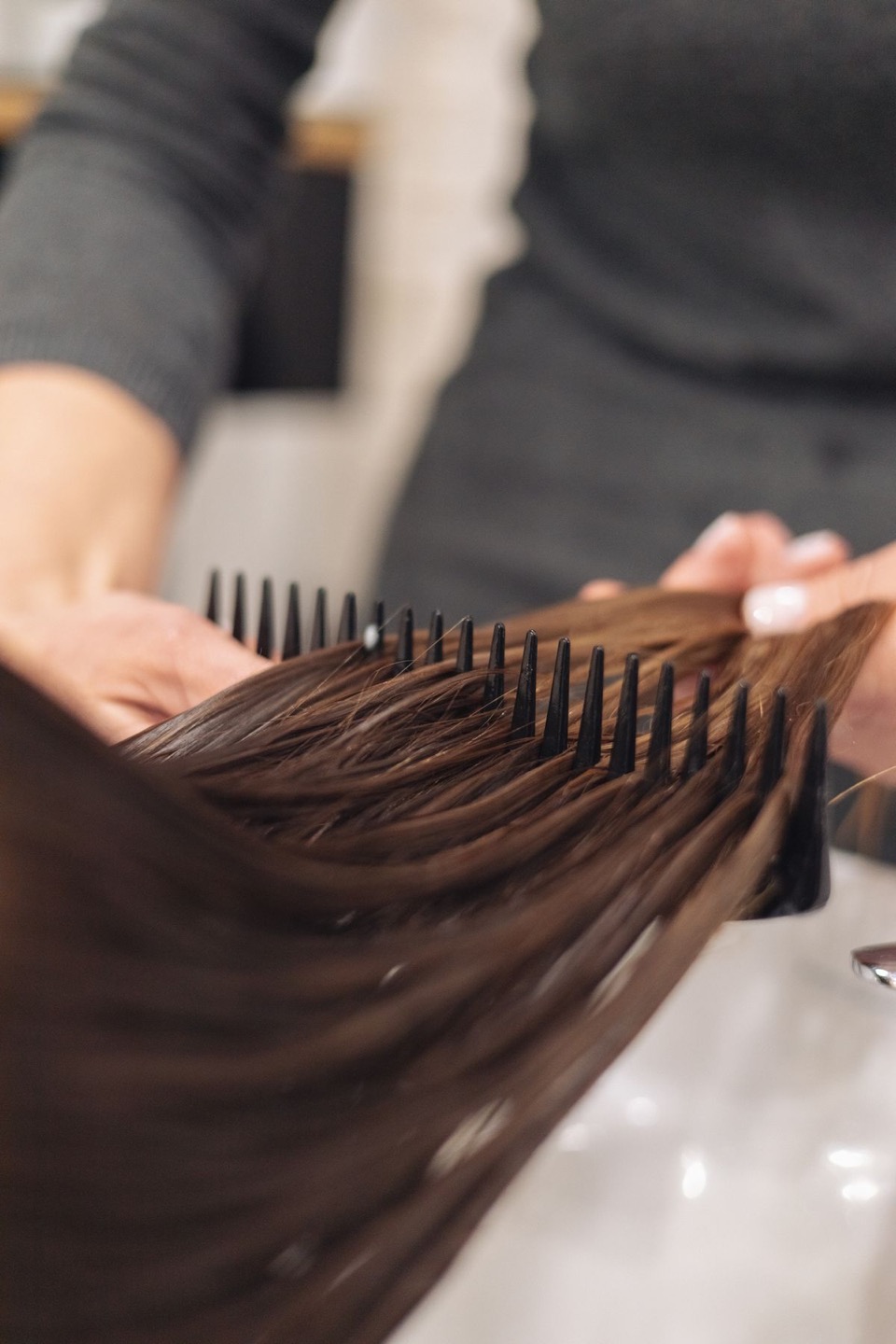 Close-up of brown hair being combed at a salon; stock art direction, not work by the studio depicted in this design concept.