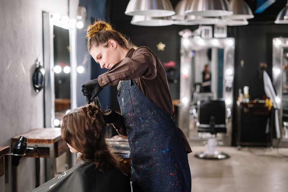 A hairstylist working on a seated person in a salon; stock photography, not Forme staff or clients.